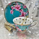 Decorative teacup and saucer with little blue wren birds and a floral design on a textured surface