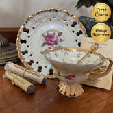 Vintage teacup with floral design on a wooden surface, next to a decorative plate and tea bags.