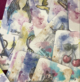 A soft watercolor deck titled “Sereni-Tea” with pen outline images, displayed in a spread showing vibrant, detailed cards.