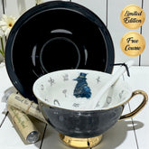Tea cup with decorative interior, black saucer, and tea leaves on a white surface.
