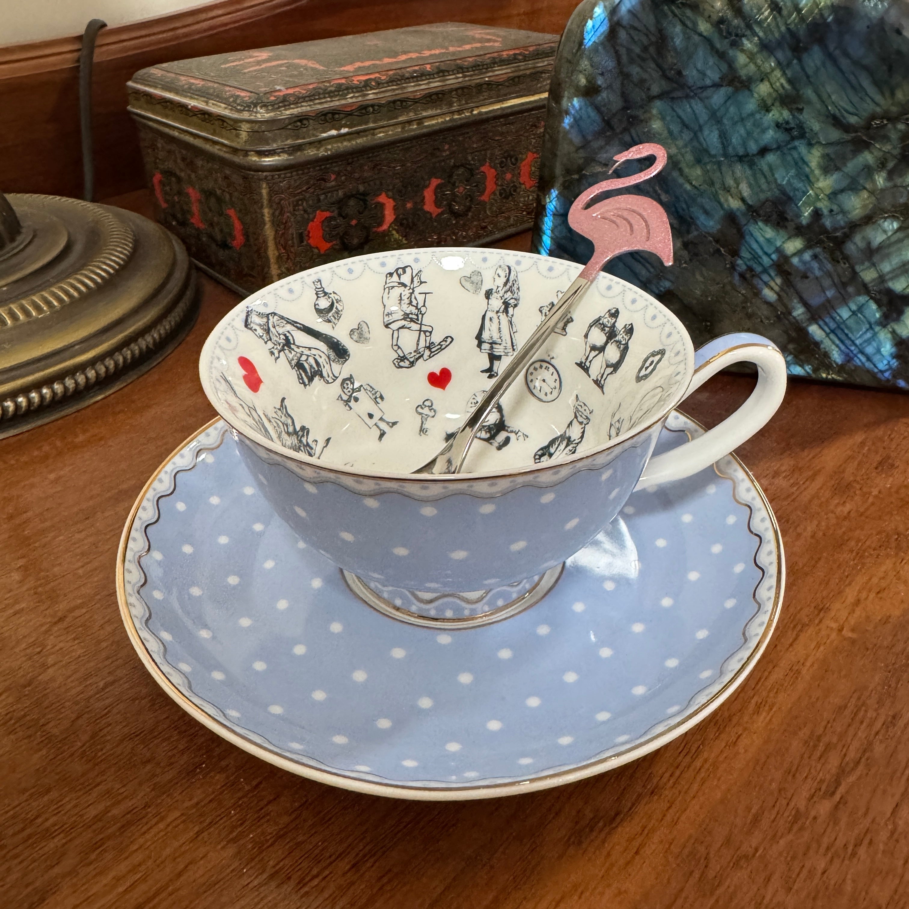 Teacup with polka dot saucer and flamingo spoon rest on a wooden surface