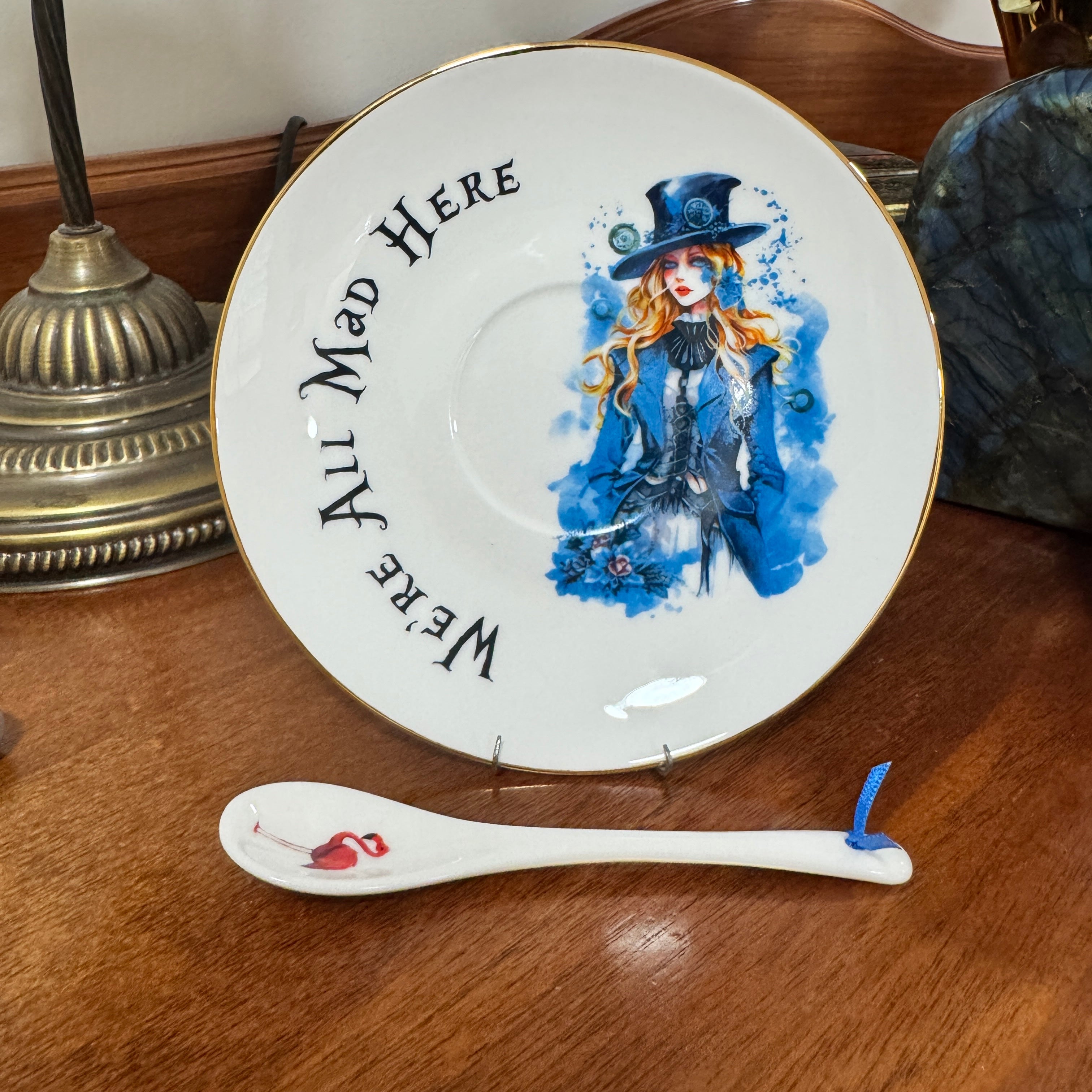 Decorative plate with Alice in Wonderland character design and a matching spoon on a wooden surface.