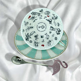 Teacup showing the black and white Alice in Wonderland illustrations inside for Tasseography or fortune