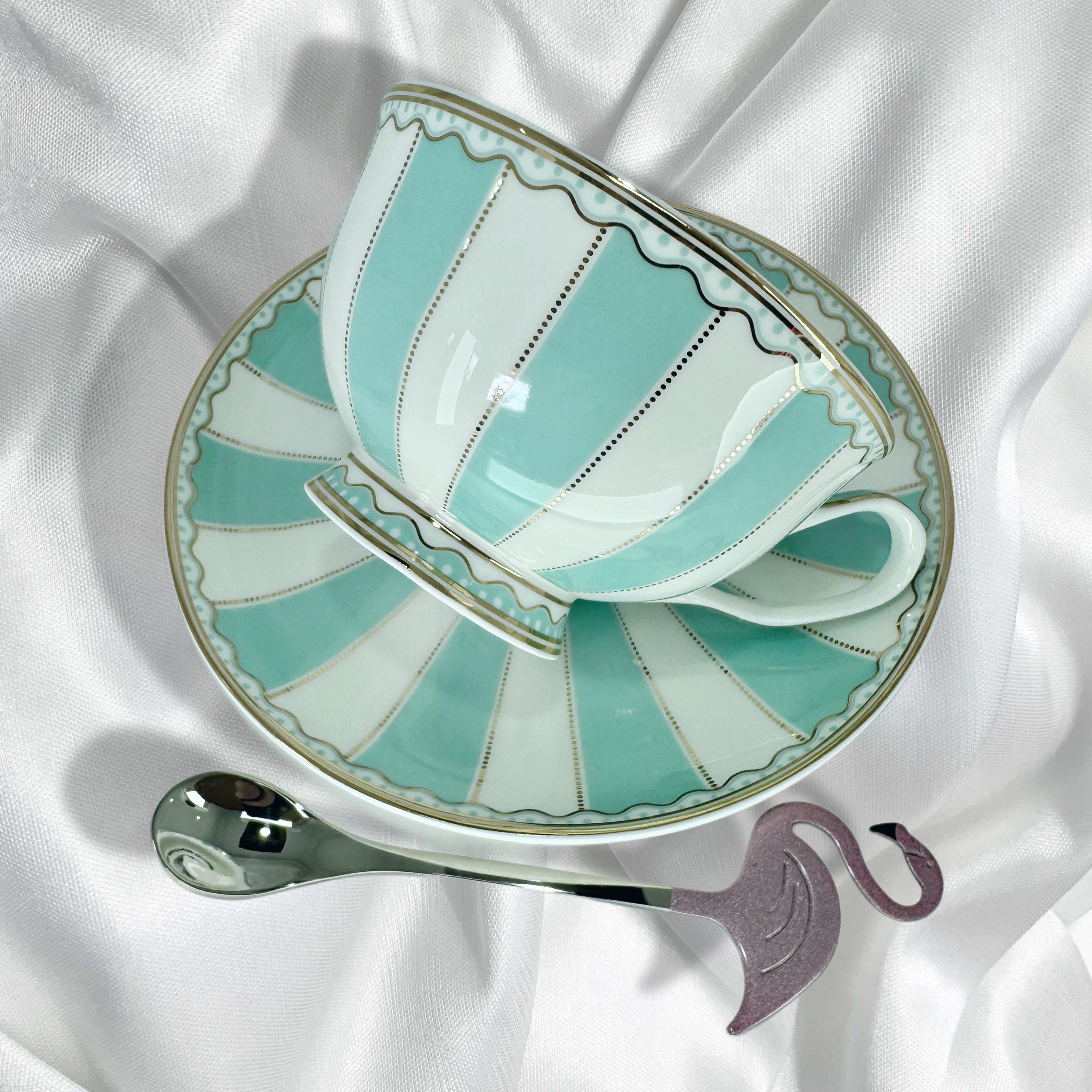 Close-up of the turquoise and white striped teacup resting on its matching saucer with a gold trim