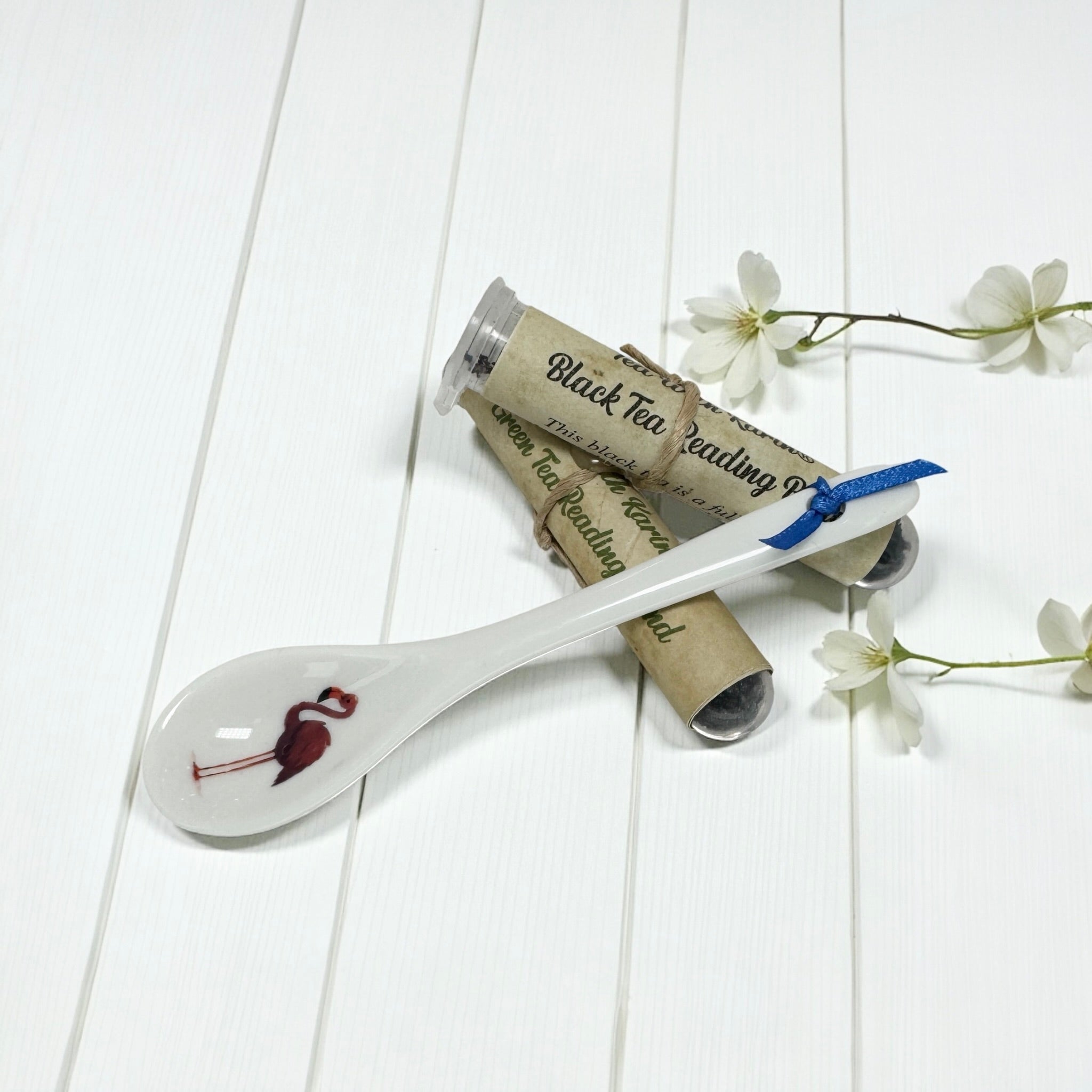 White ceramic spoon with a detailed flamingo illustration, wrapped with Black Tea Reading blend samples.