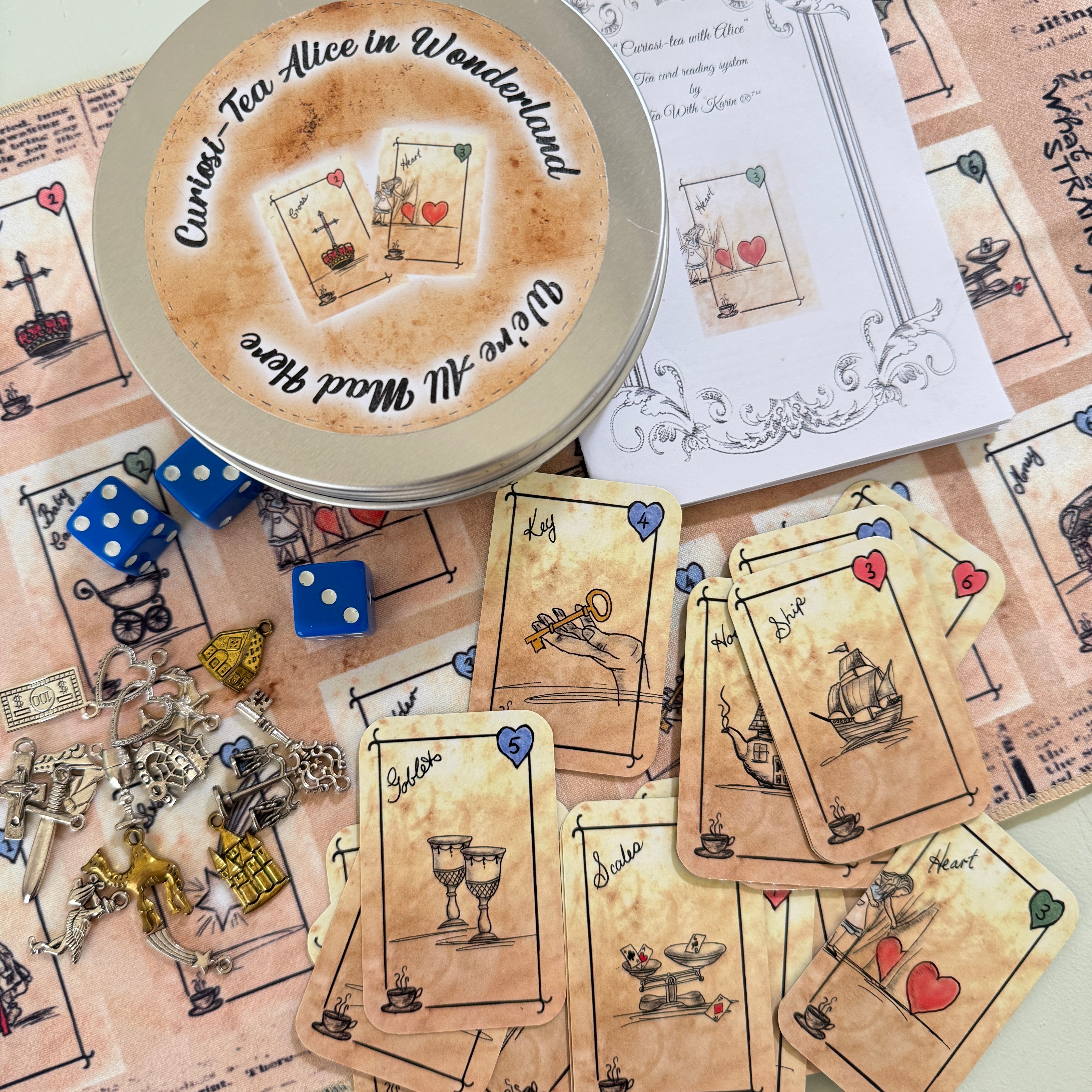 Tea party set with cards, dice, and a tin labeled 'Curious Tea Alice in Wonderland'.