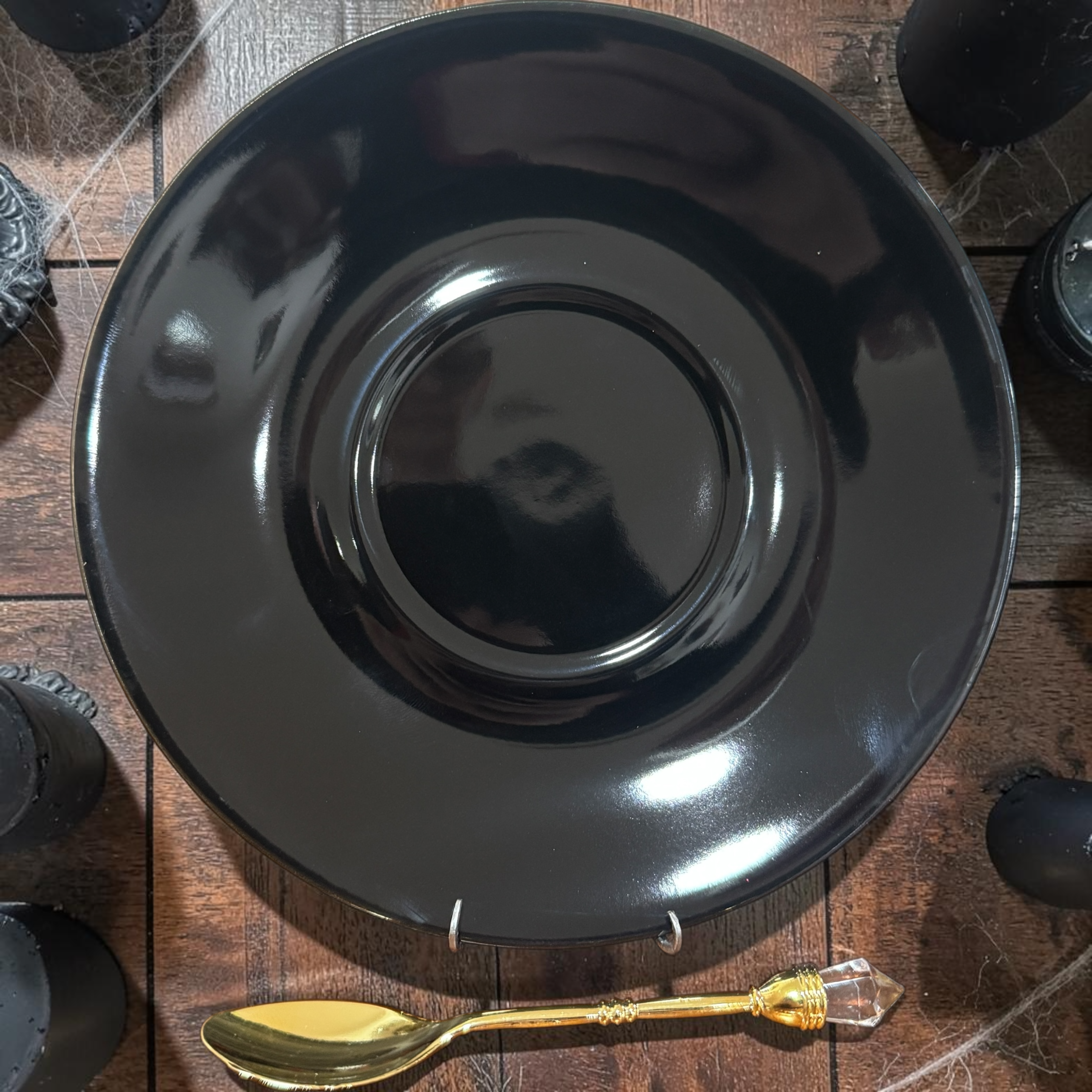 Jet black saucer with a gold crystal-topped teaspoon