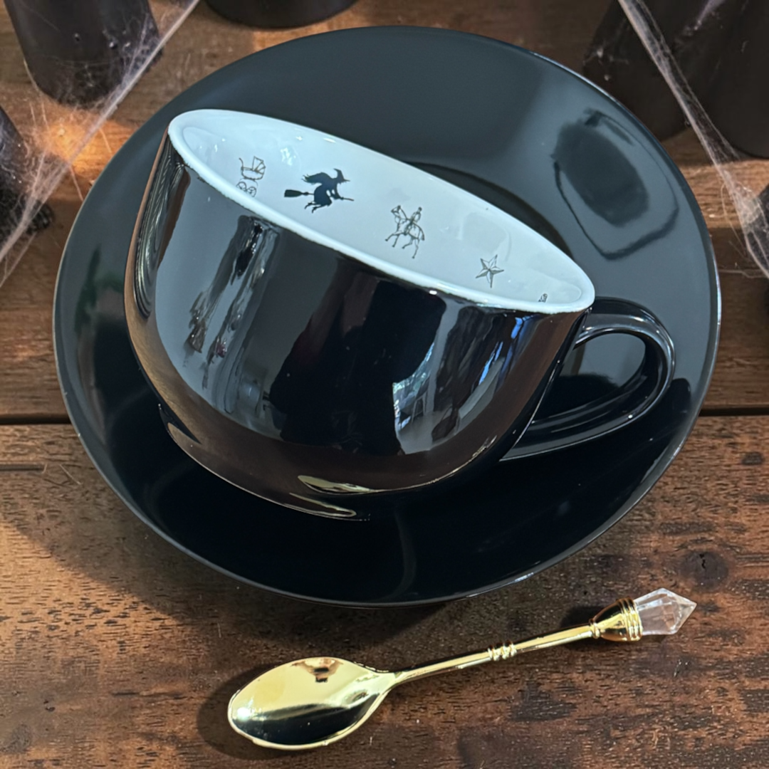 Side view of the glossy jet black witchy teacup and saucer