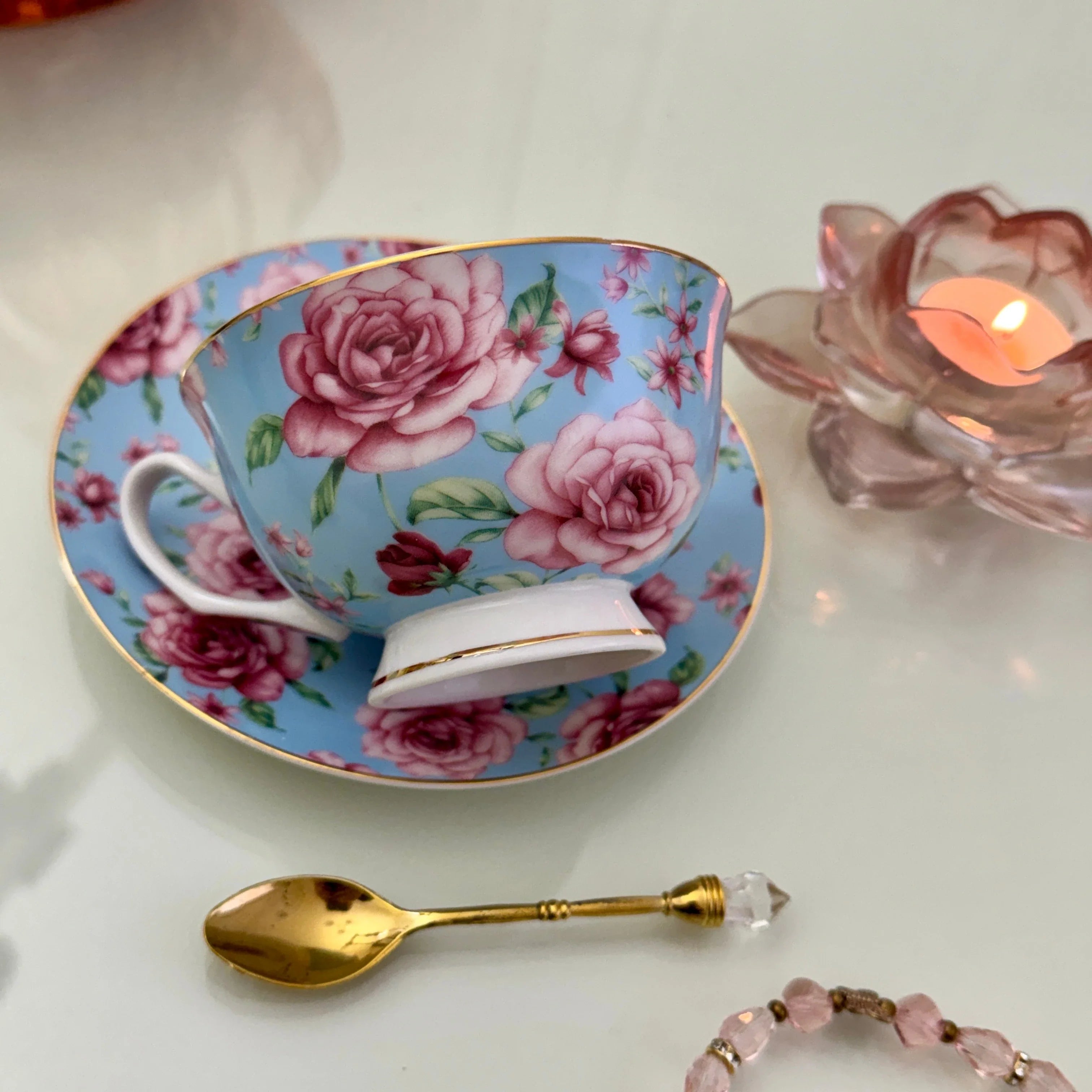 Right side view of blue pink rose floral tea leaf reading teacup tilted on matching saucer with Tea With Karin stamp visible on base