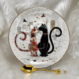 Decorative saucer with two cats and a gold spoon on a white background