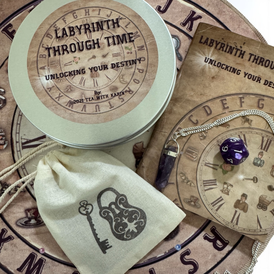 Complete Labyrinth Through Time destiny reading set laid out, showing the alphabet and number time mats, antique-style divination cards (including the '3 Months' and 'Hopes' cards), the guidebook, and the pendulum/d20 die.