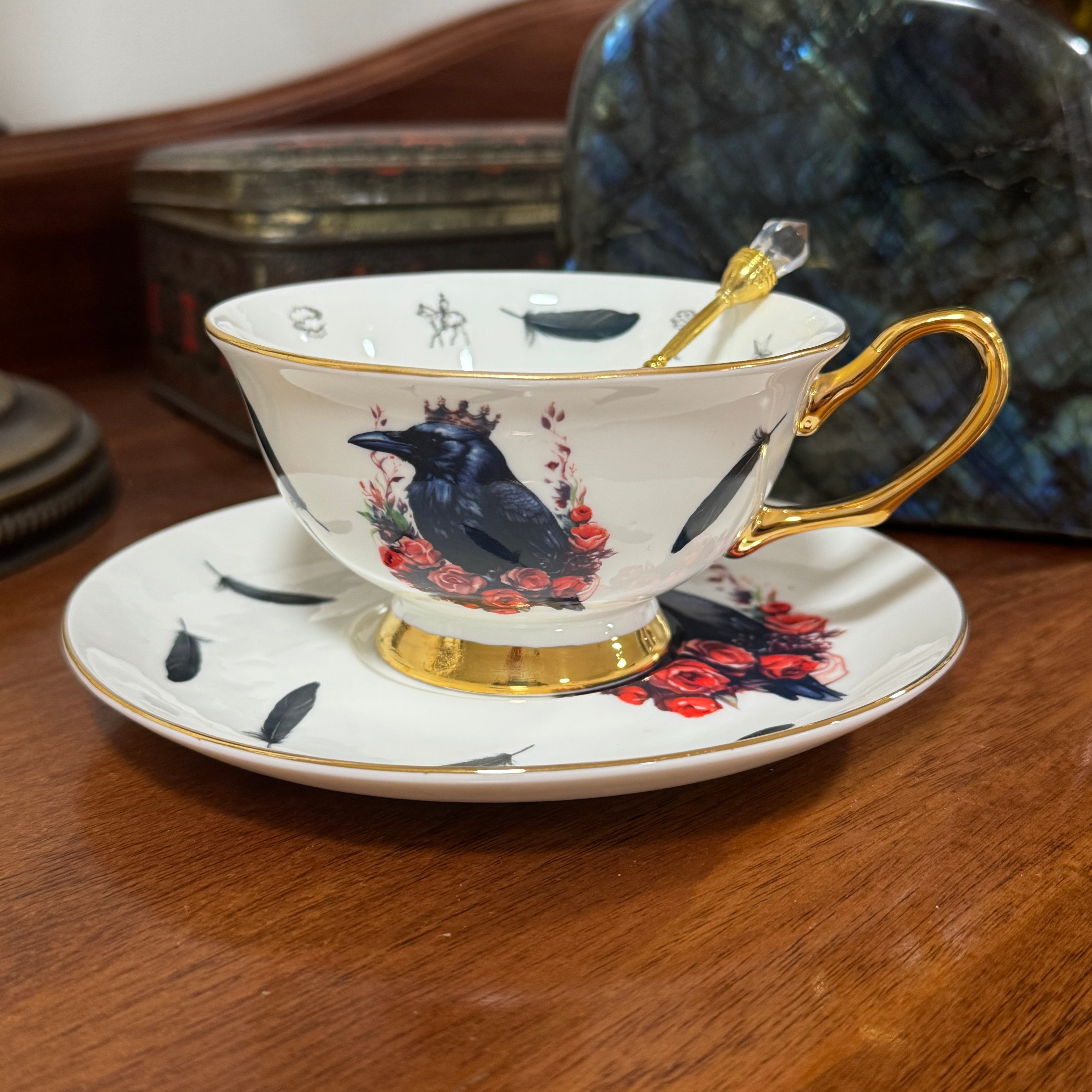 Teacup with decorative design featuring a crow and flowers on a wooden surface.