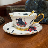 Teacup with decorative design featuring a crow and flowers on a wooden surface.