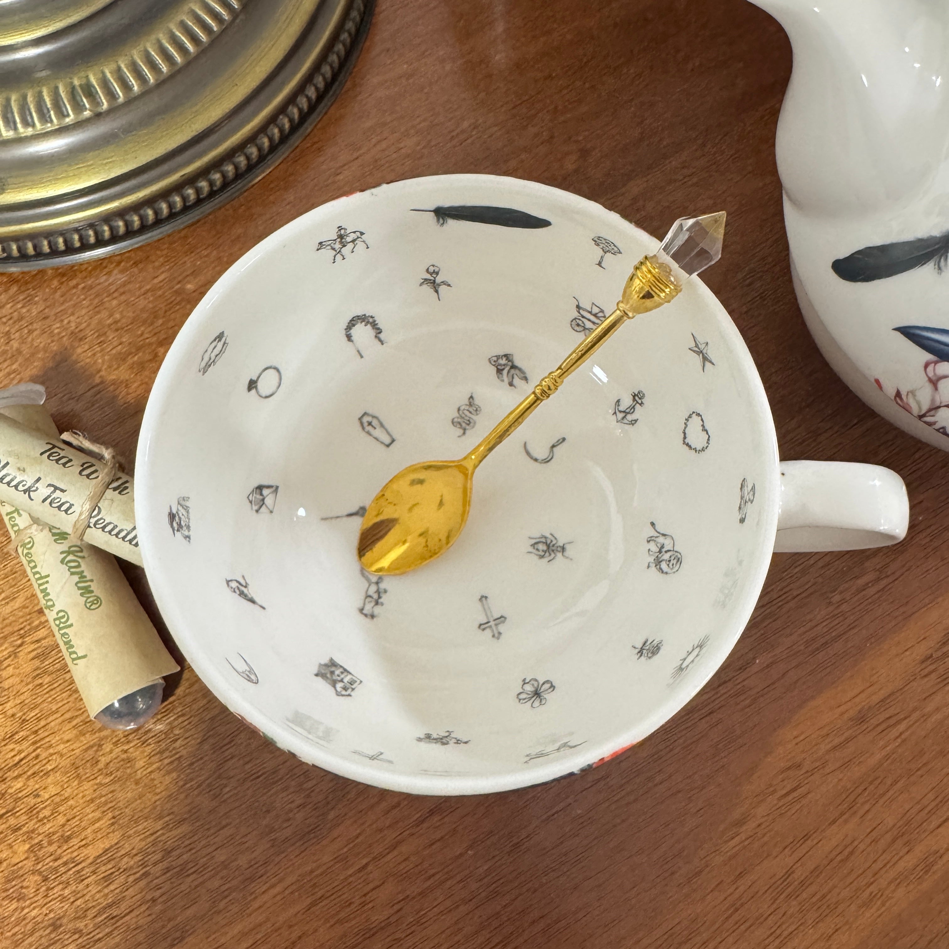 Teacup with gold spoon and tea packaging on a wooden surface