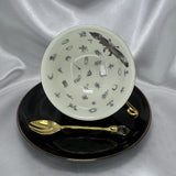 Teacup on its side showing the white interior with a large colourful skull-moth and small black classic fortune-telling symbols.