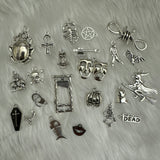 Set of 23 Halloween-themed charms in a black coffin box, each with spooky details, accompanied by a meanings sheet, ideal for charm casting, divination, and Halloween parties.