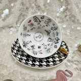 Alice in Wonderland teacup and saucer set with gold accents, accompanied by a matching teaspoon and tea samples, perfect for tea leaf reading and divination