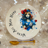 Whimsical Alice in Wonderland tea set with gold-accented teacup, saucer, and teaspoon, featuring vivid symbols inside the cup, perfect for tea leaf reading and divination