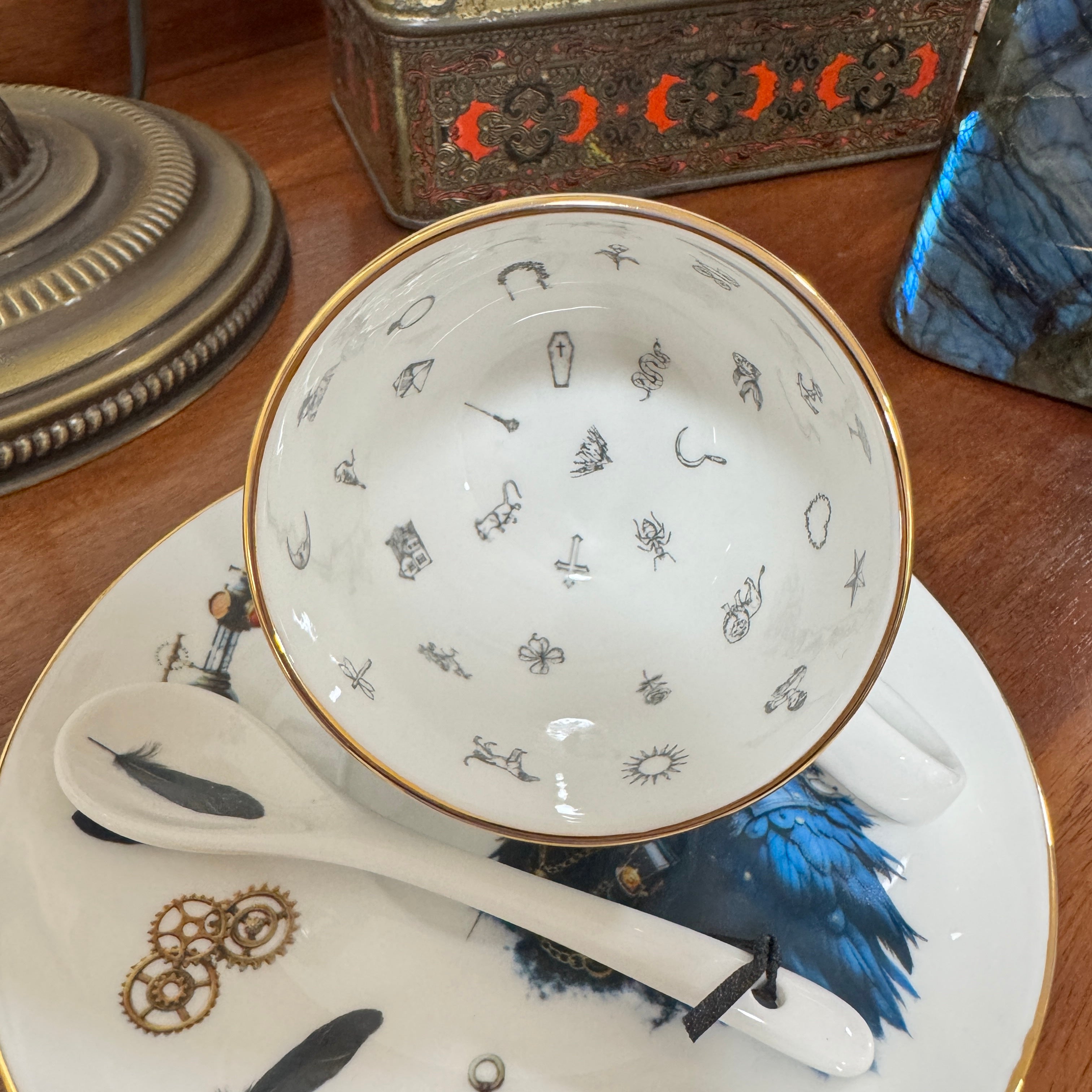 Teacup with decorative patterns on a saucer with similar designs, placed on a wooden surface.