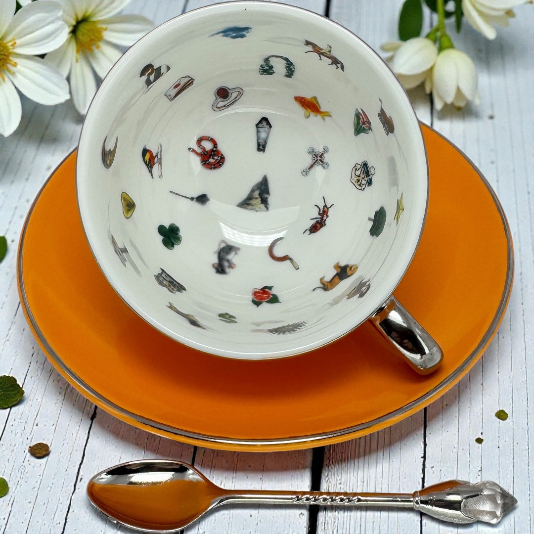 Close up view of the white interior of an orange tea cup showing various symbolic icons used for tea leaf reading and fortune telling.