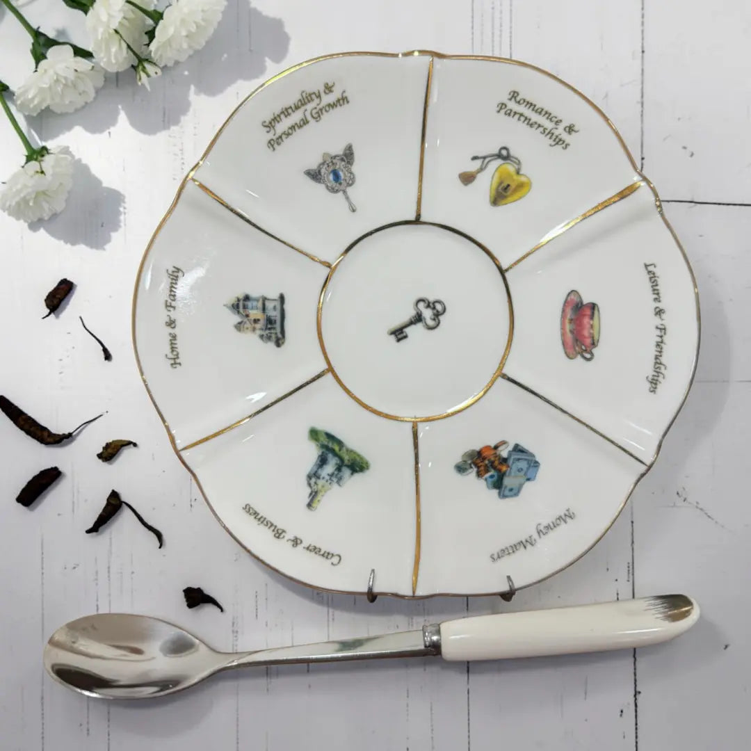 Labyrinth life wheel saucer with six illustrated sections and a 24ct gold rim, with a white-handled spoon