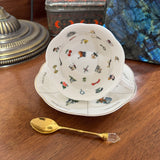Teacup with decorative design on a wooden surface with a gold spoon.