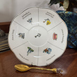 Decorative plate with symbolic illustrations and a gold spoon on a wooden surface