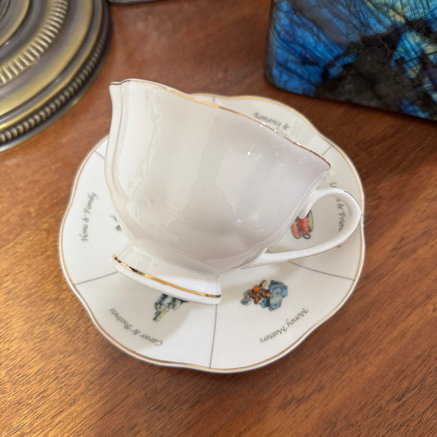 White teacup and saucer with floral designs on a wooden surface