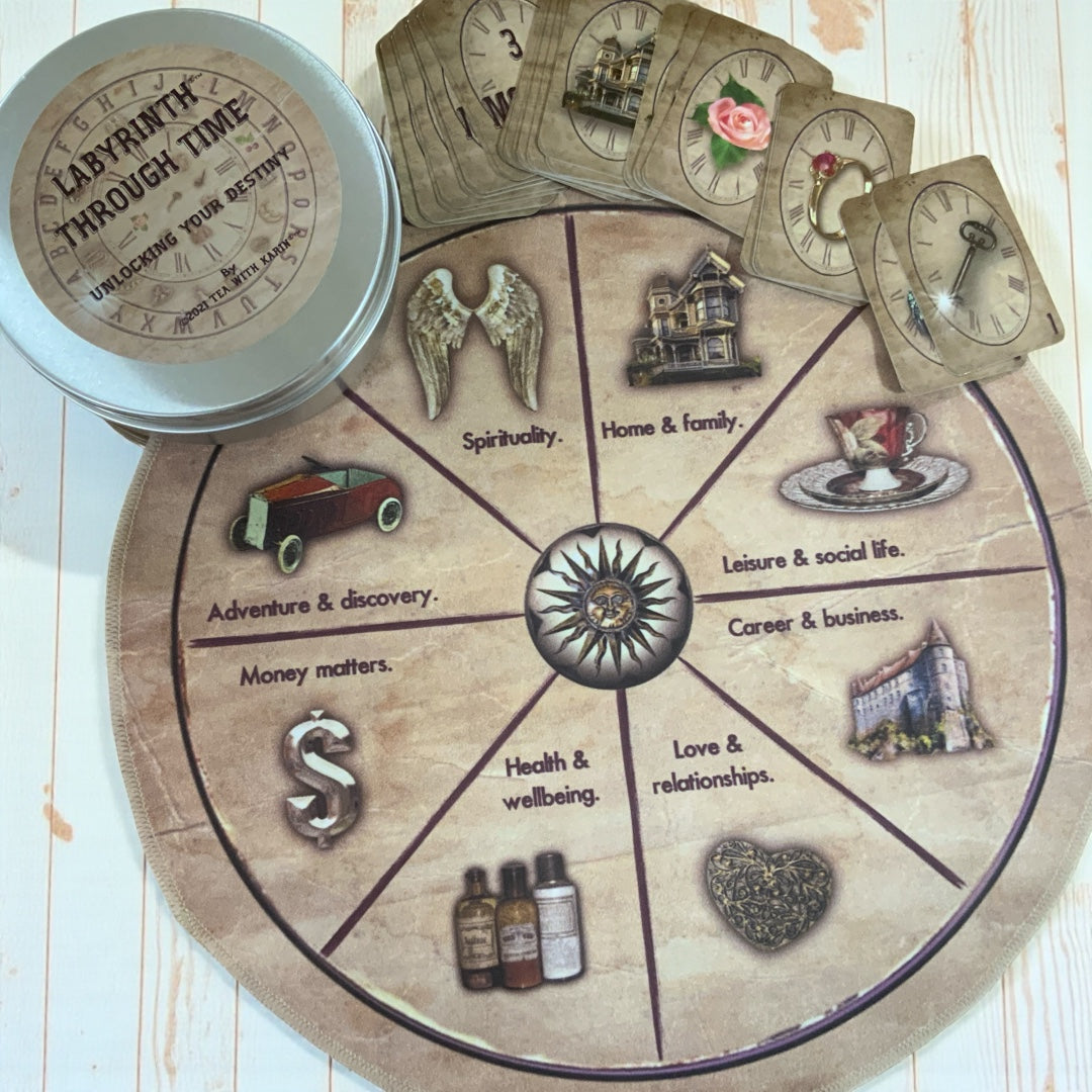 Close-up of the Labyrinth Through Time destiny charm casting kit components, including the storage tin, guidebook, drawstring key and padlock pouch, a purple d20 die, and an amethyst crystal pendulum on a silver chain.