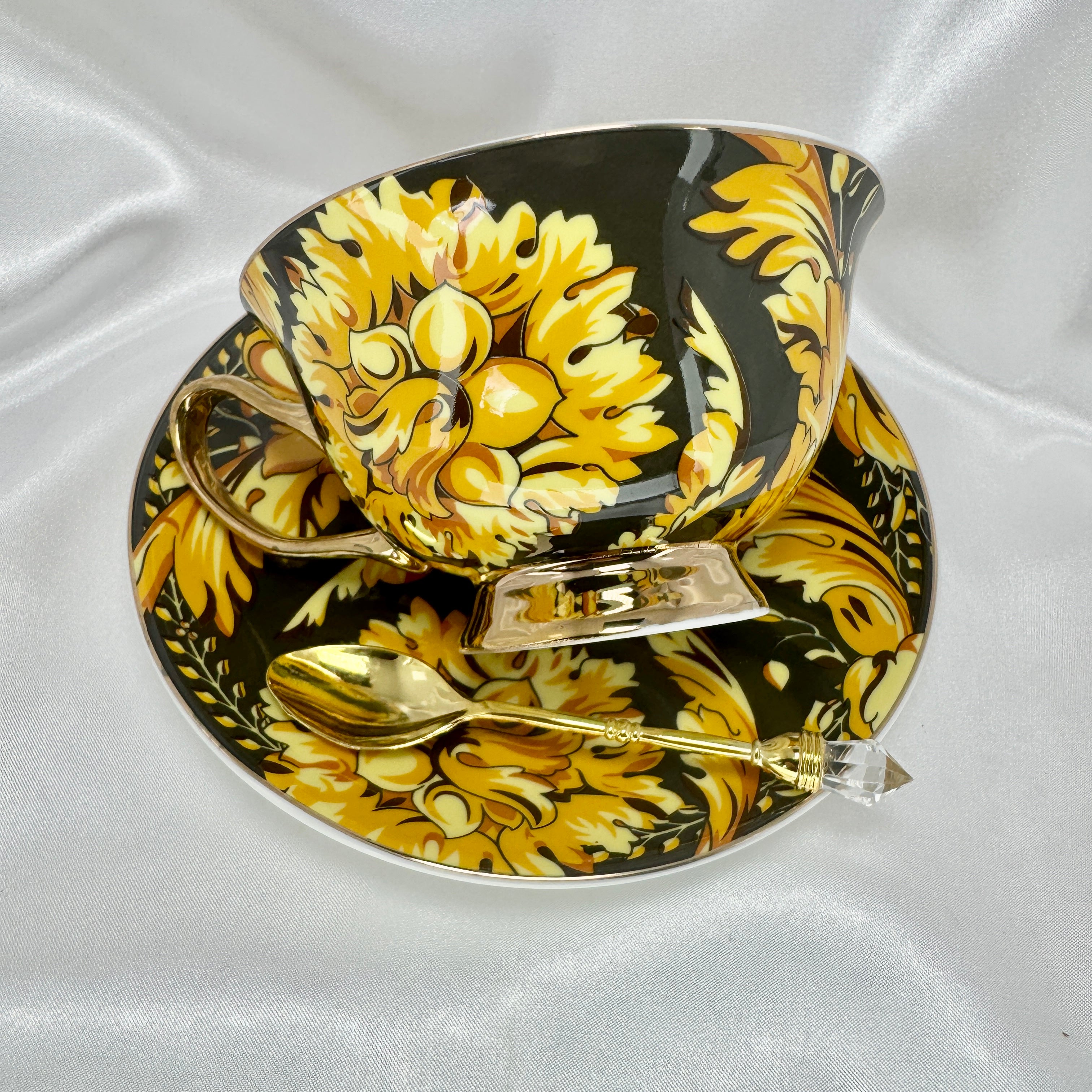 Left side view of the black and gold teacup and saucer set, showing the opulent gold and black floral pattern