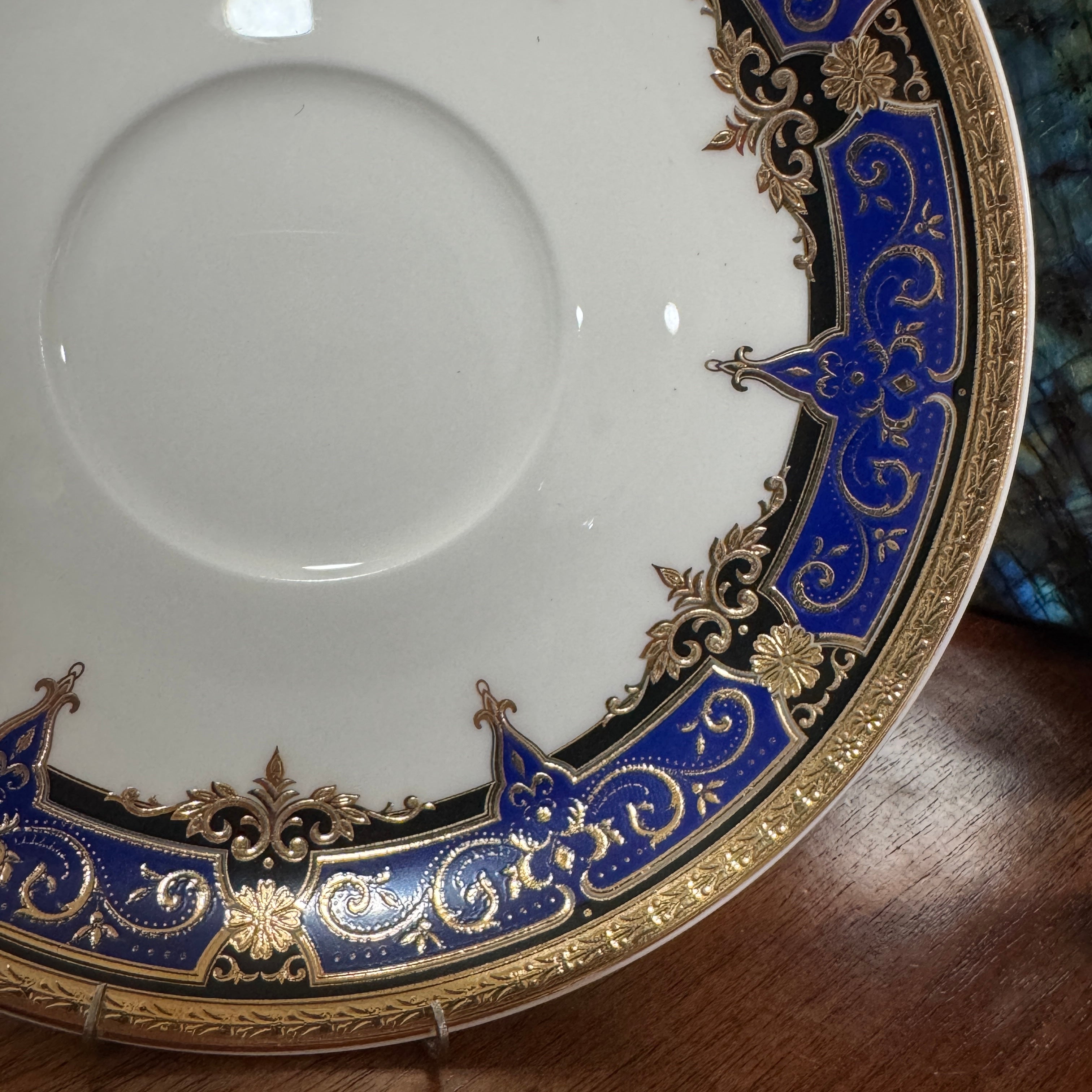 Decorative ceramic plate with blue and gold rim on a wooden surface
