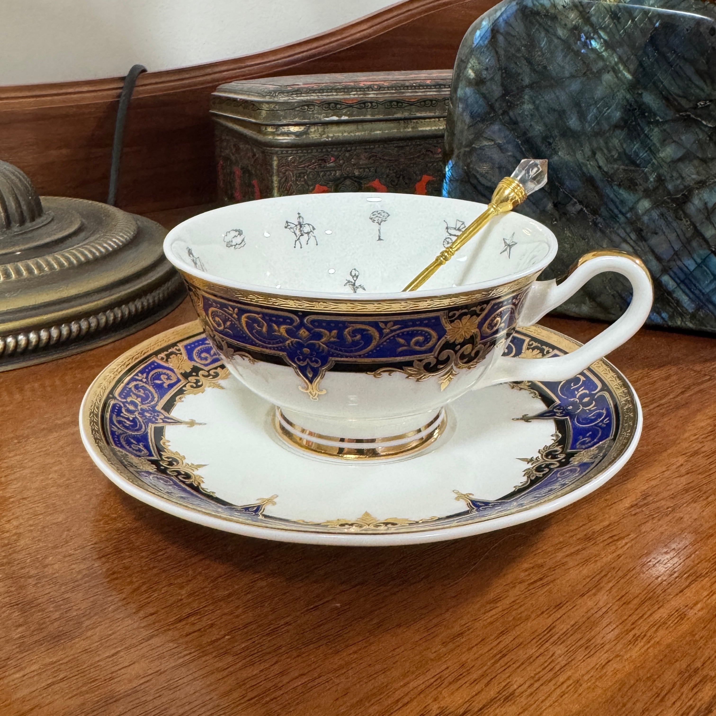Decorative teacup with blue and gold accents on a saucer, placed on a wooden surface.