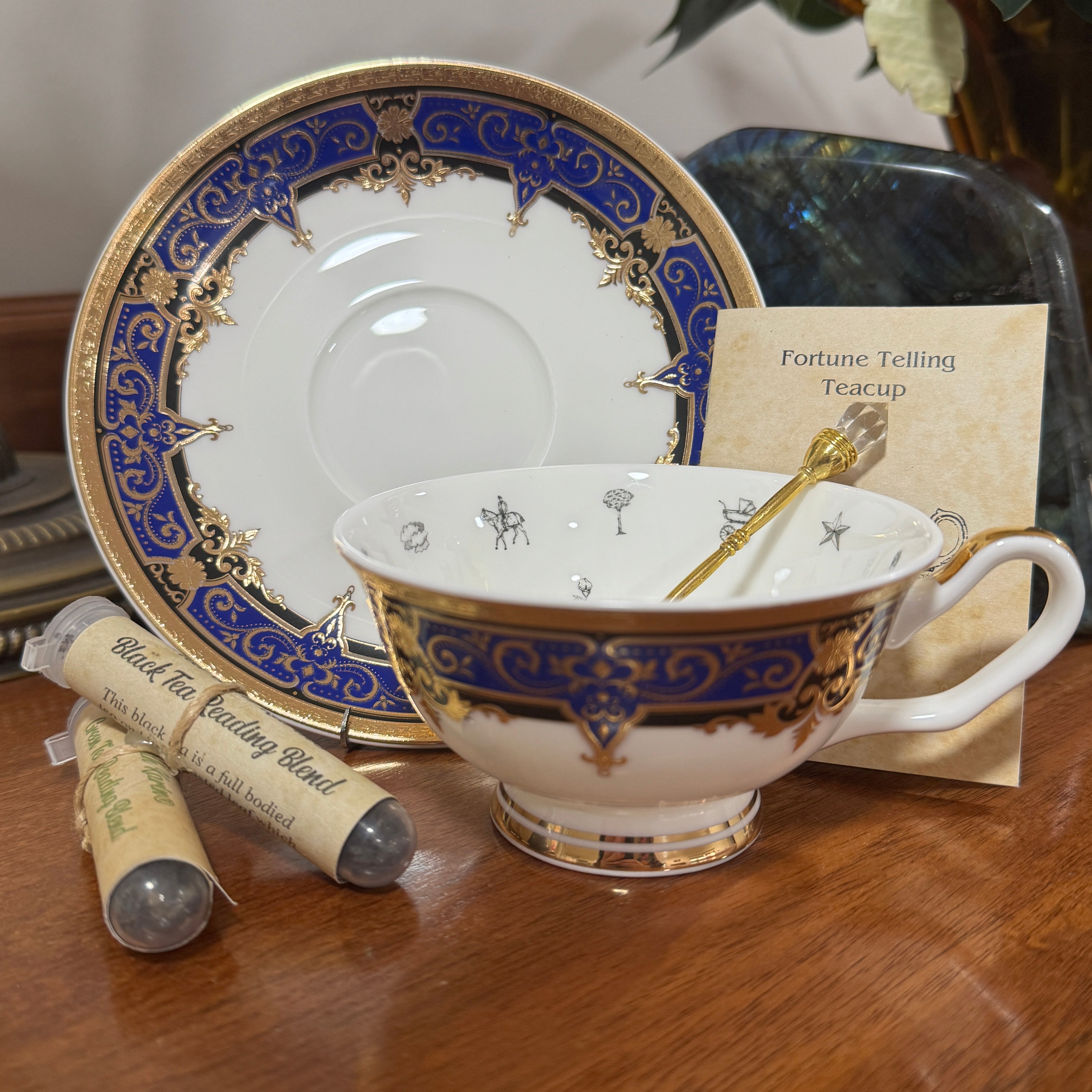 Decorative teacup with saucer, tea lights, and a card on a wooden surface
