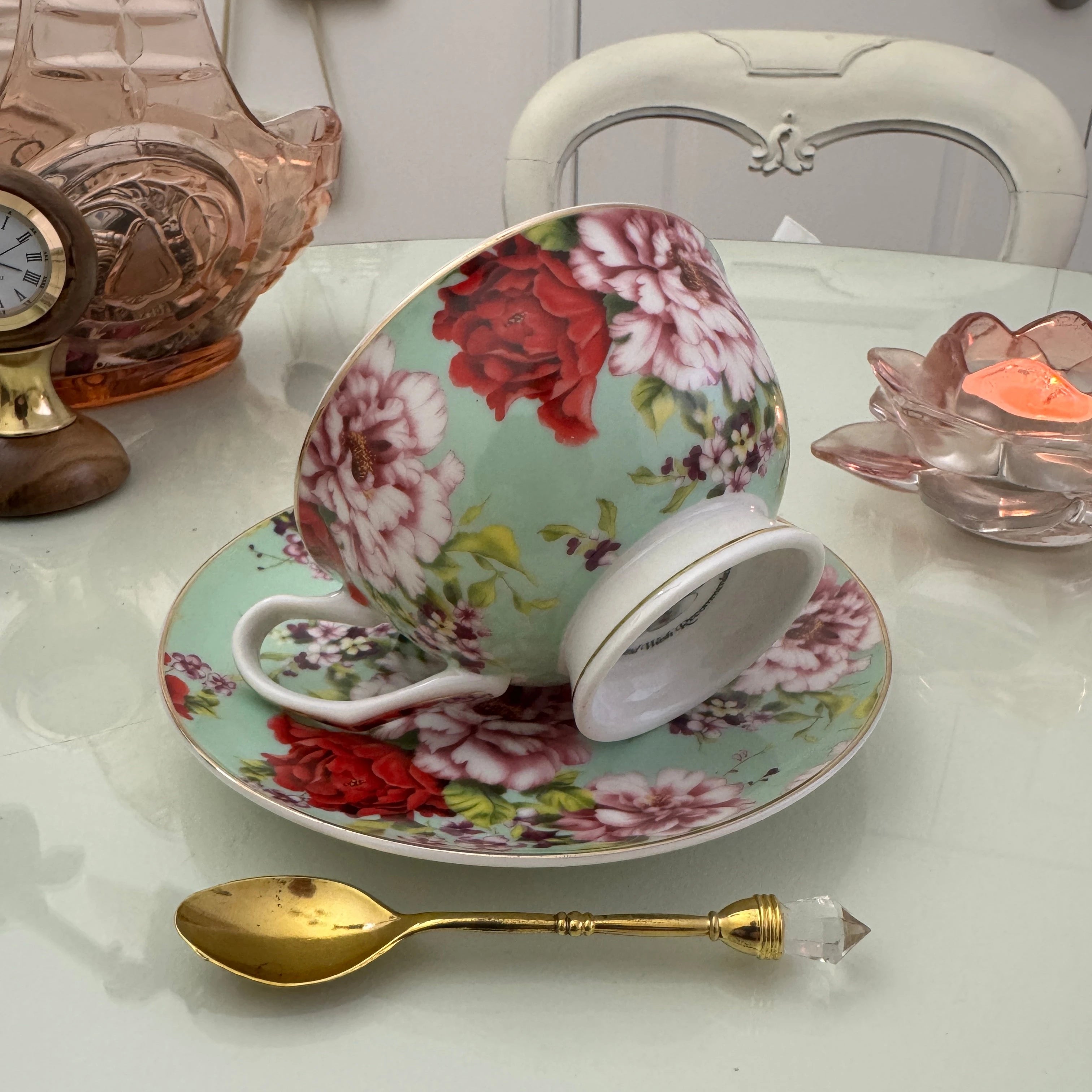 Right side view of mint red rose floral tea leaf reading teacup tilted on matching saucer with Tea With Karin stamp visible on base