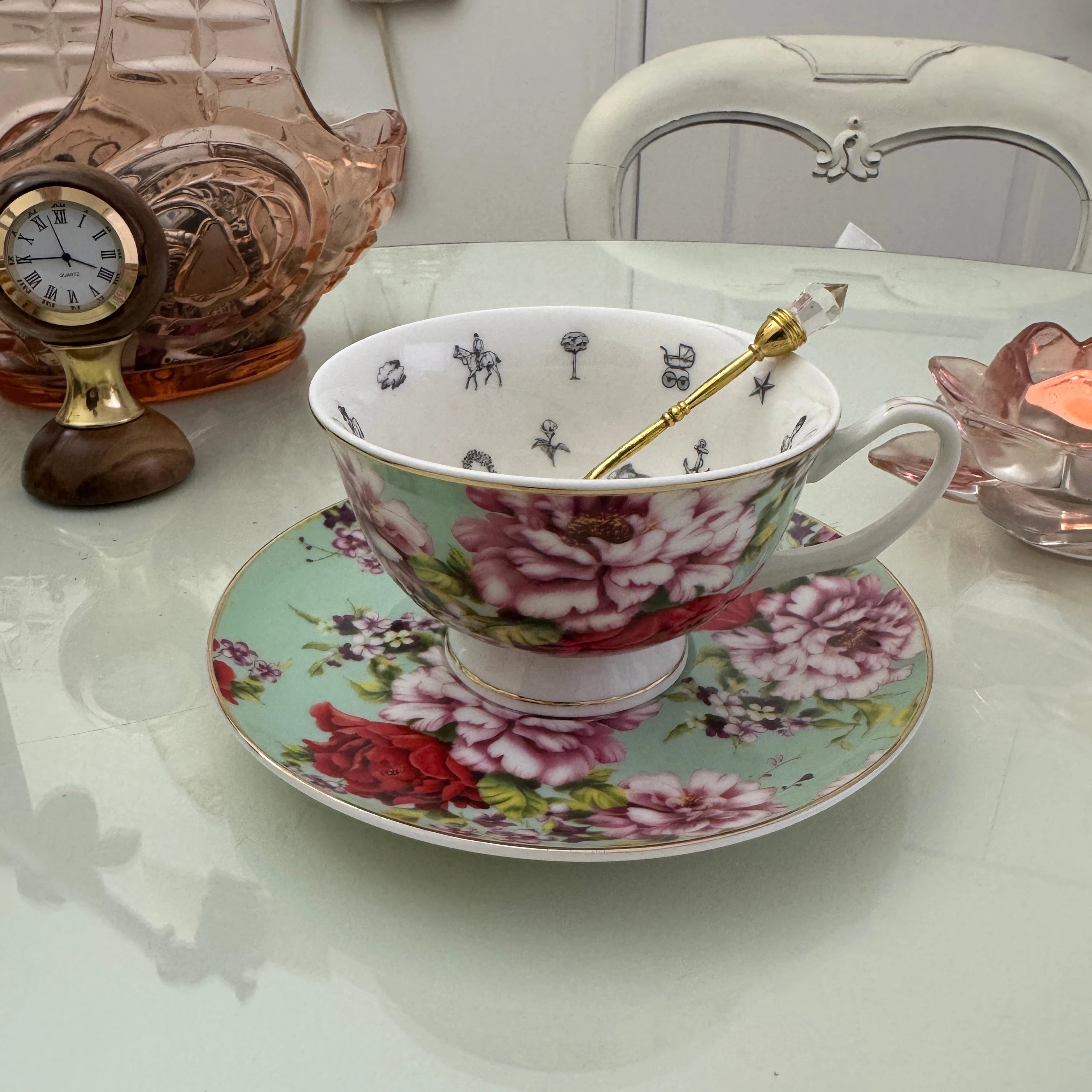 Mint red rose floral tea leaf reading teacup and saucer set with gold crystal teaspoon resting in cup, upright view showing divination symbols inside