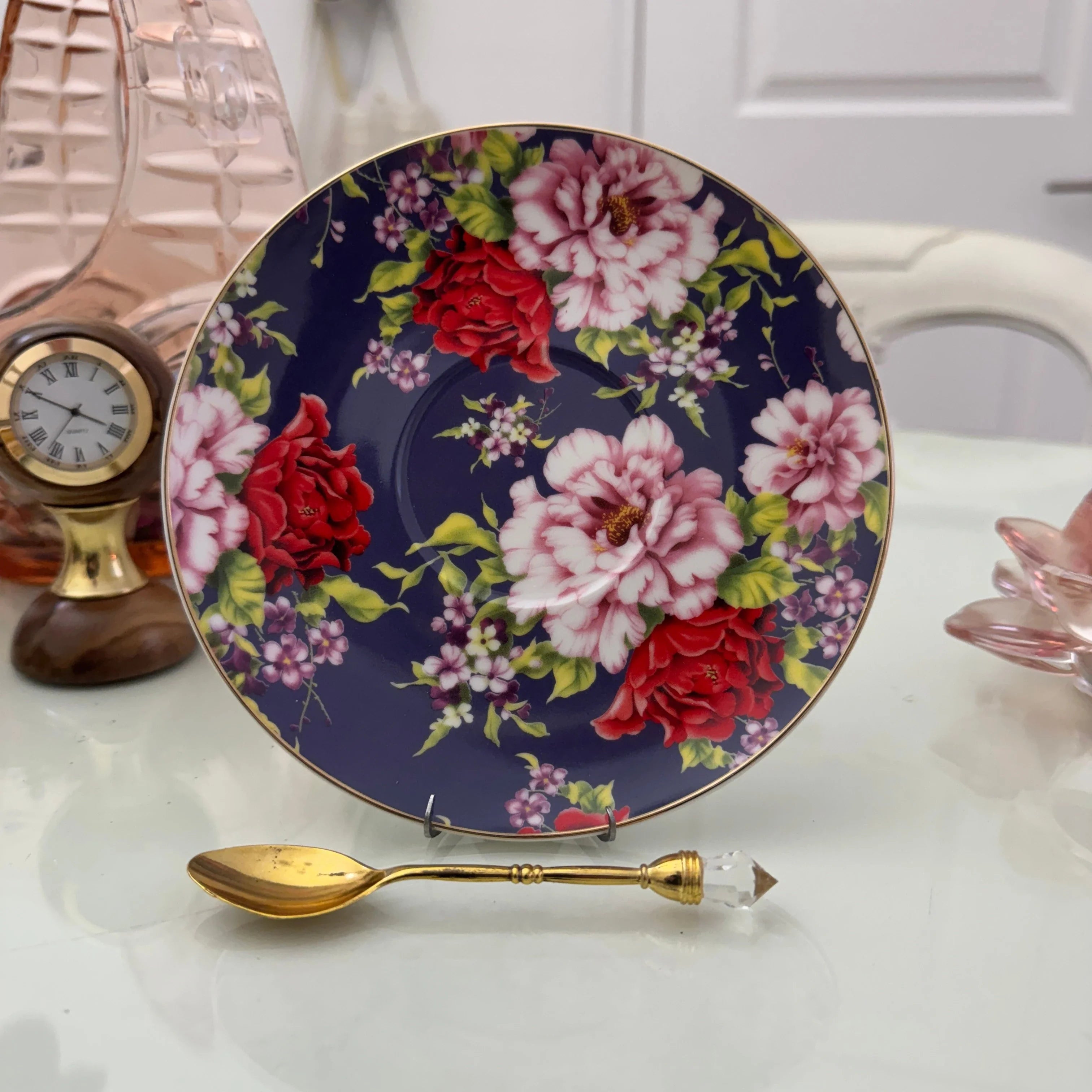 Navy red rose floral ceramic saucer with gold rim from tea leaf reading cup set, displayed with gold crystal teaspoon