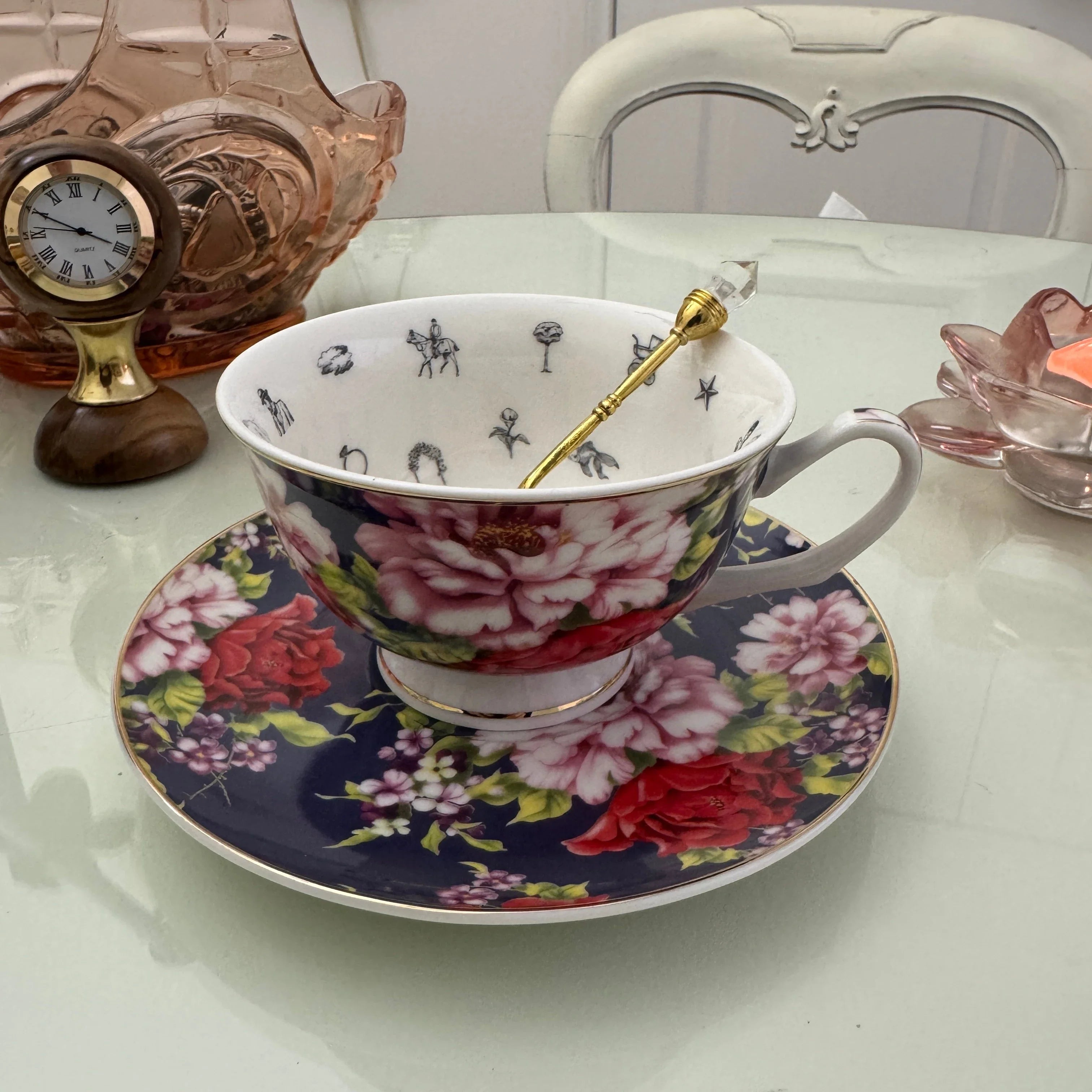 Navy red rose floral tea leaf reading teacup and saucer set with gold crystal teaspoon resting in cup, upright view showing divination symbols inside