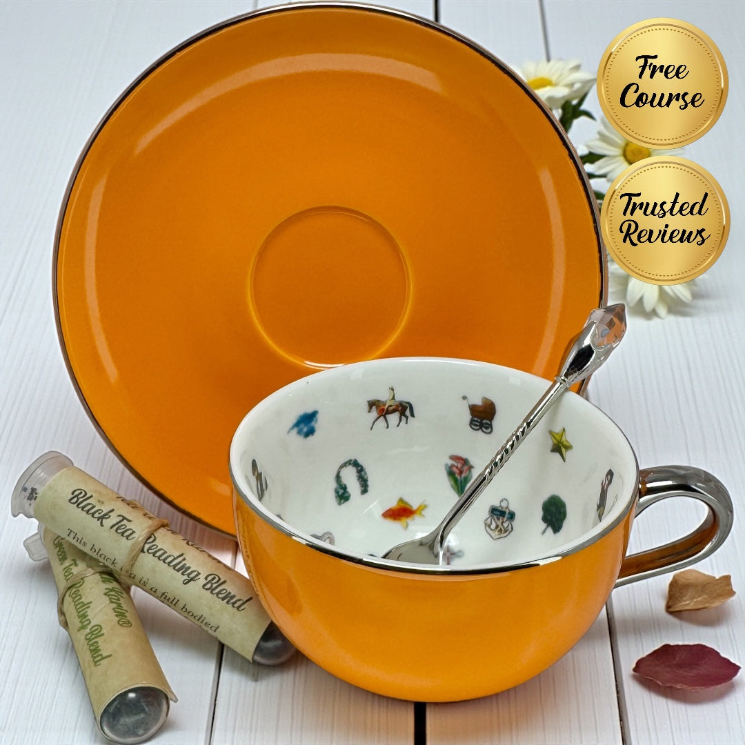 Vibrant orange tea cup and saucer set with a silver decorative spoon and two sample tubes of black and green tea reading blends