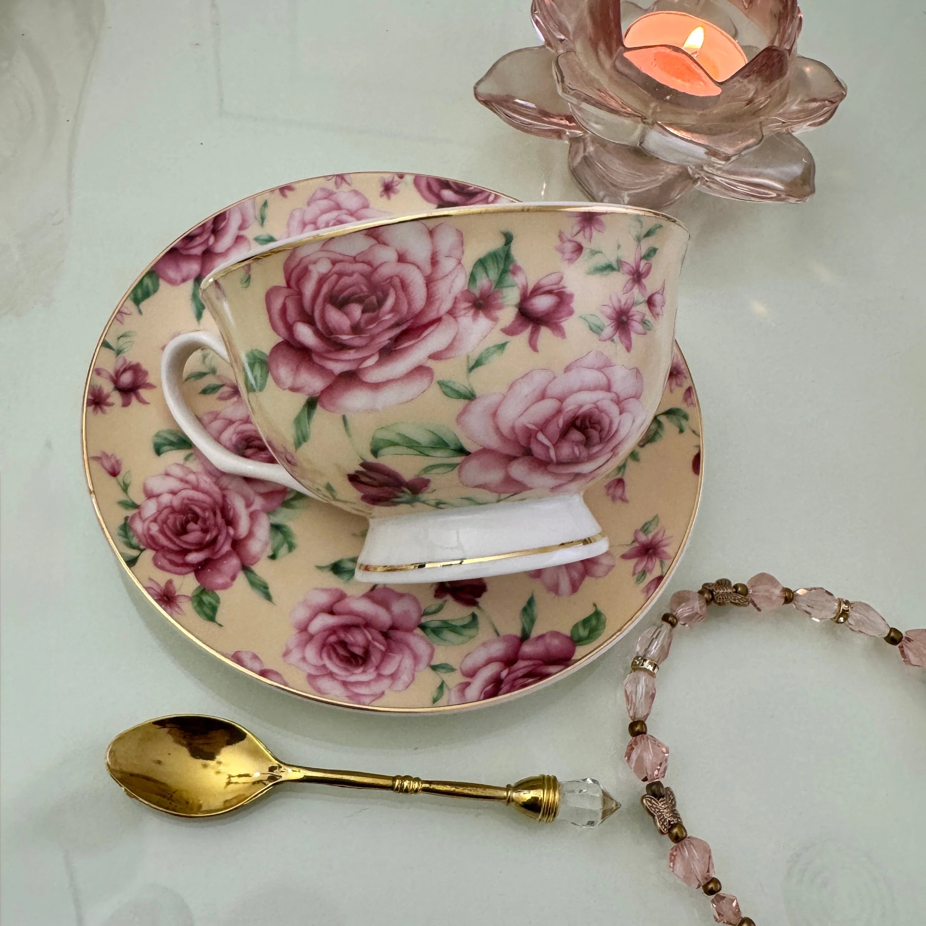 Right side view of pink butter rose floral tea leaf reading teacup tilted on matching saucer with Tea With Karin stamp visible on base