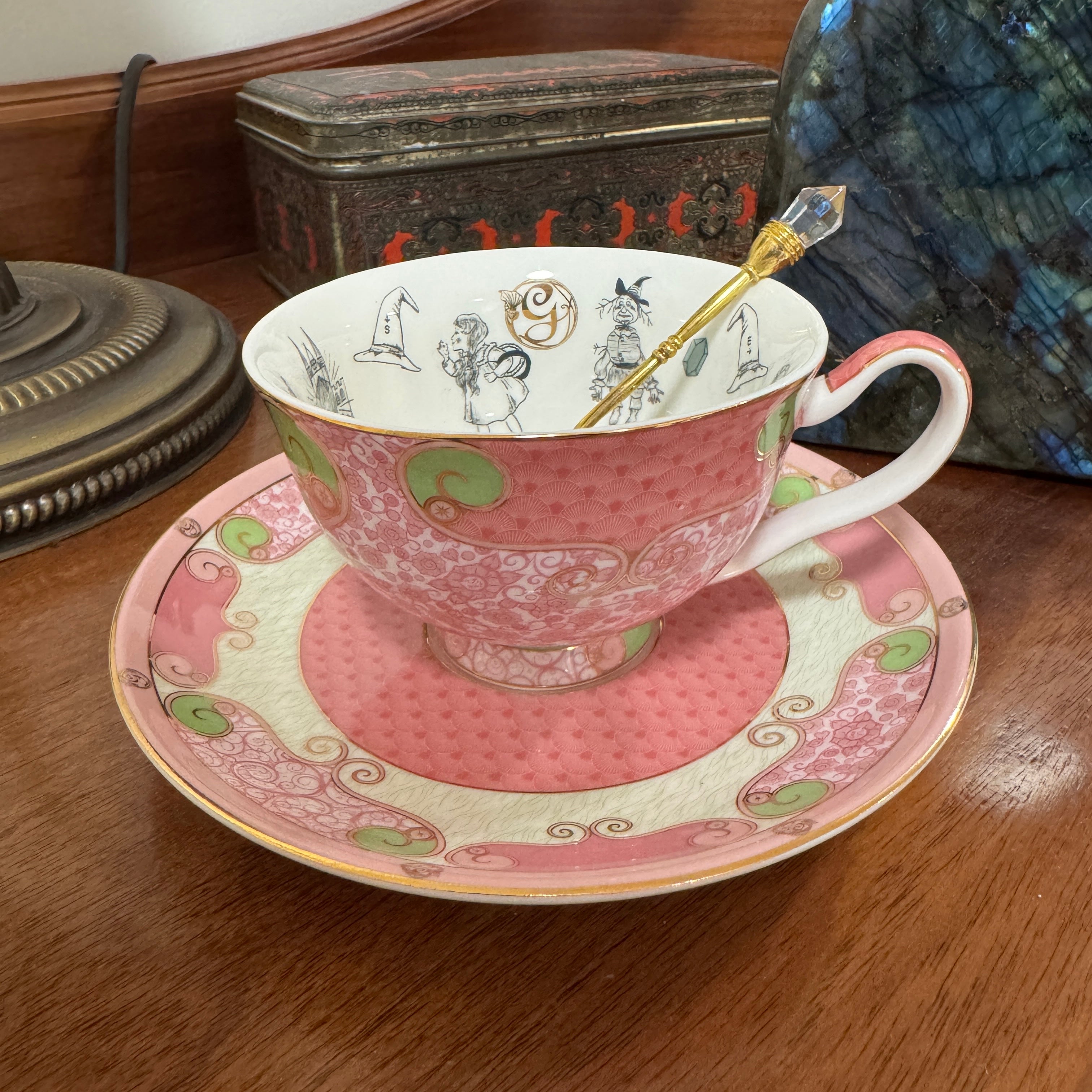 Pink teacup and saucer with decorative patterns on a wooden surface