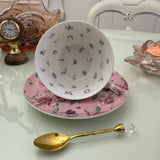 Inside view of pink rose floral tasseography teacup showing tea leaf reading symbols, resting on matching saucer with gold crystal teaspoon