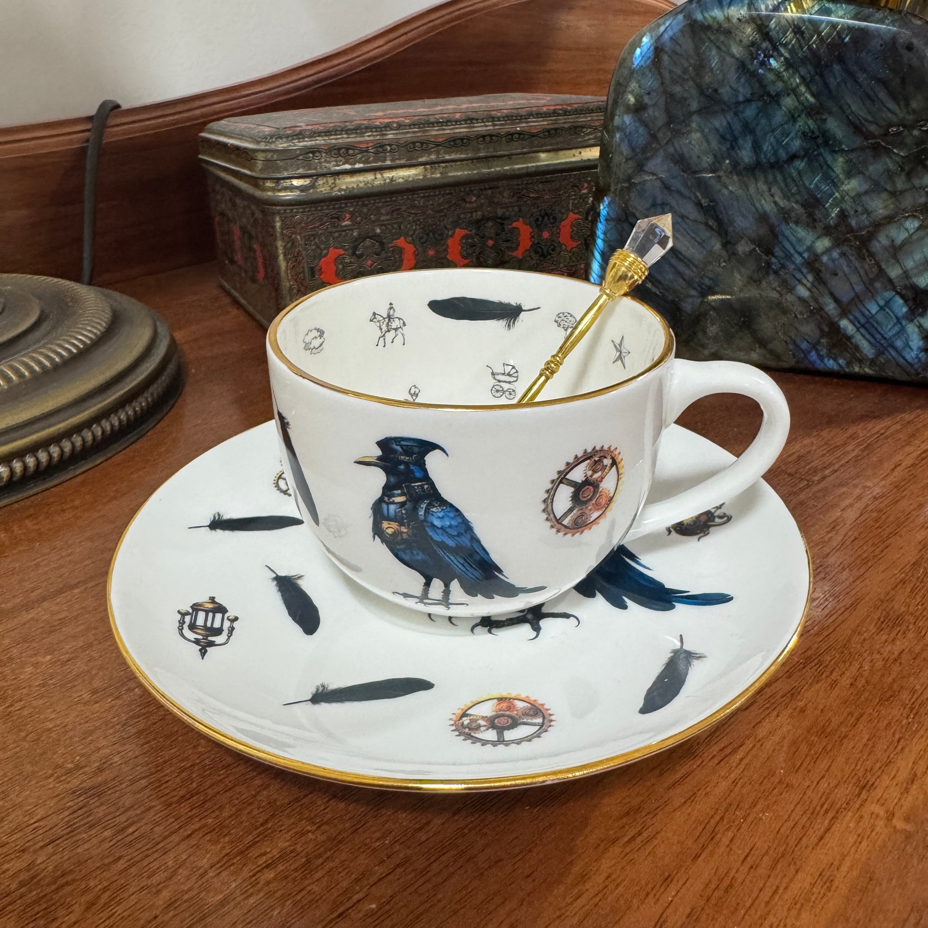 Decorative teacup and saucer with bird design on a wooden surface