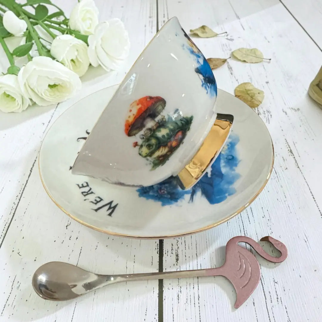 Alice teacup tilted on its saucer showing the Caterpillar on a red spotted toadstool, ready for a tea leaf reading