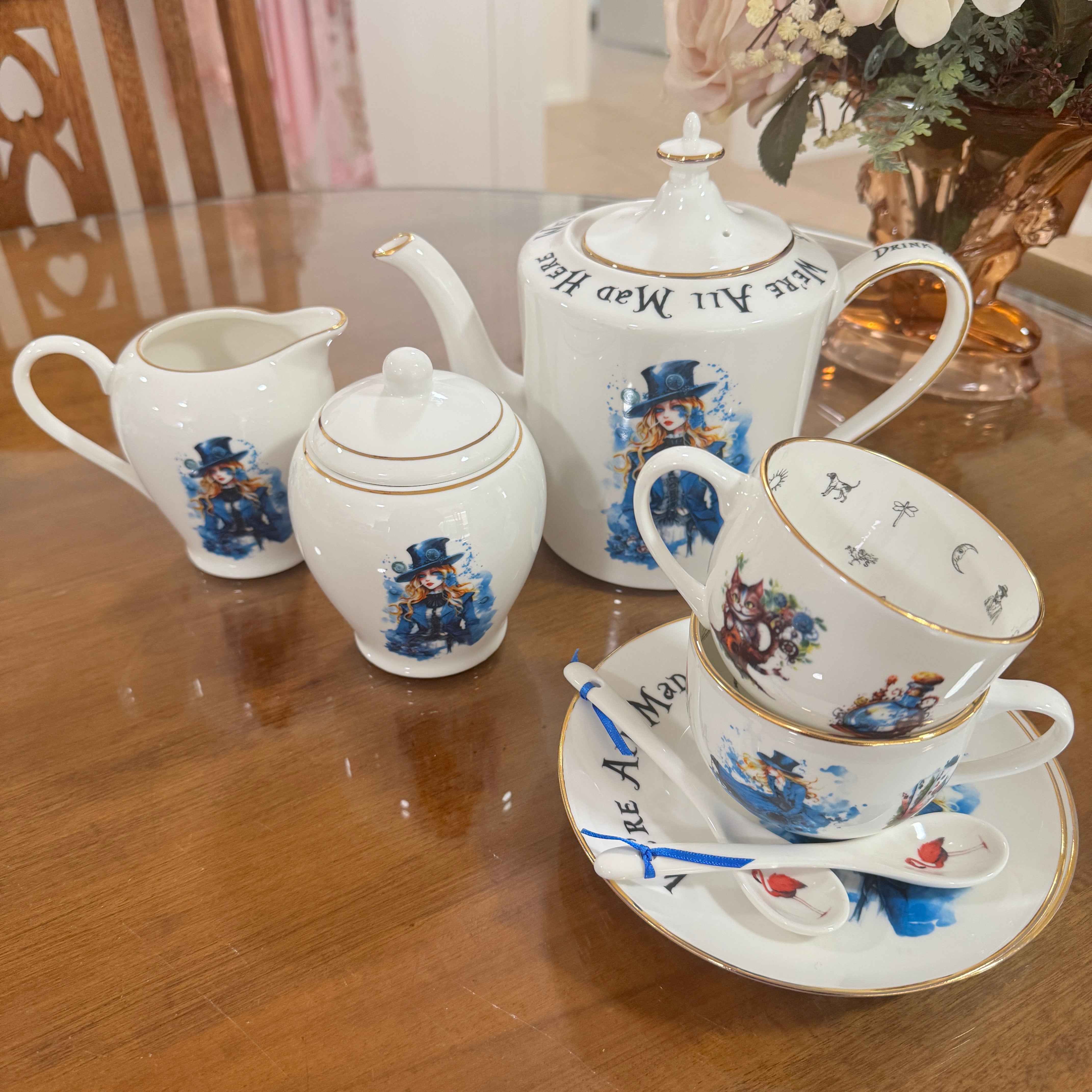Tea set with decorative teapot, cups, and saucer on a wooden table.
