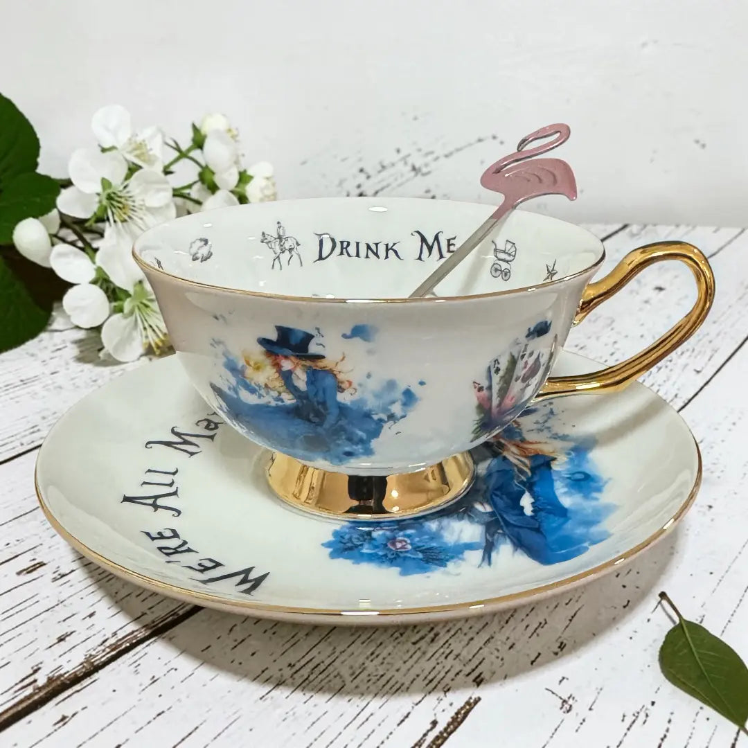 Alice in Wonderland tea leaf reading cup on its saucer, with blue watercolour Alice artwork and gold handle and foot