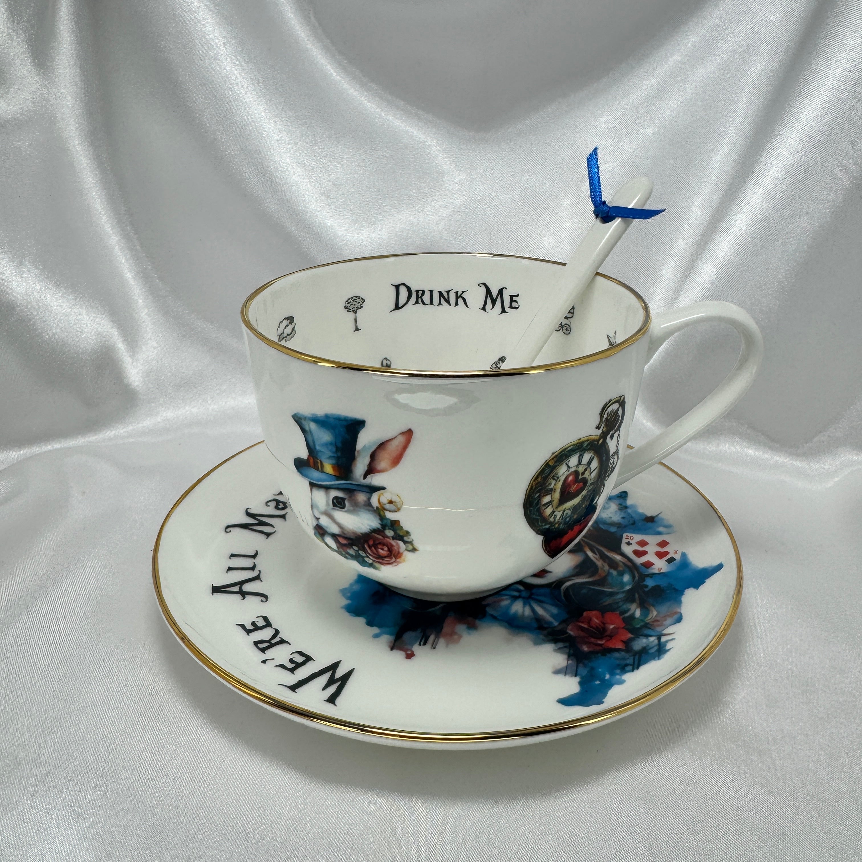 Teacup and saucer with Alice in Wonderland design on a white fabric background