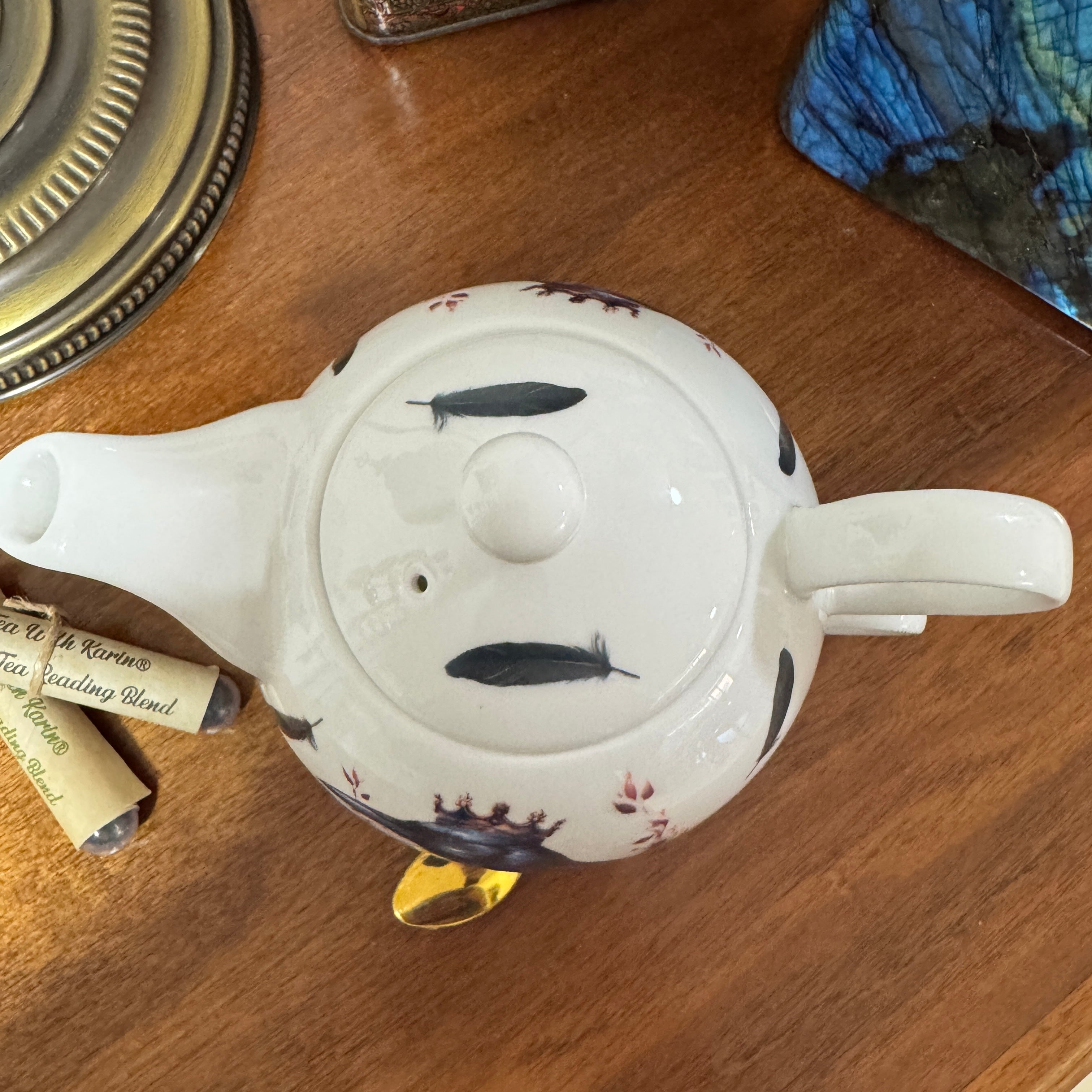 White teapot with decorative elements on a wooden surface