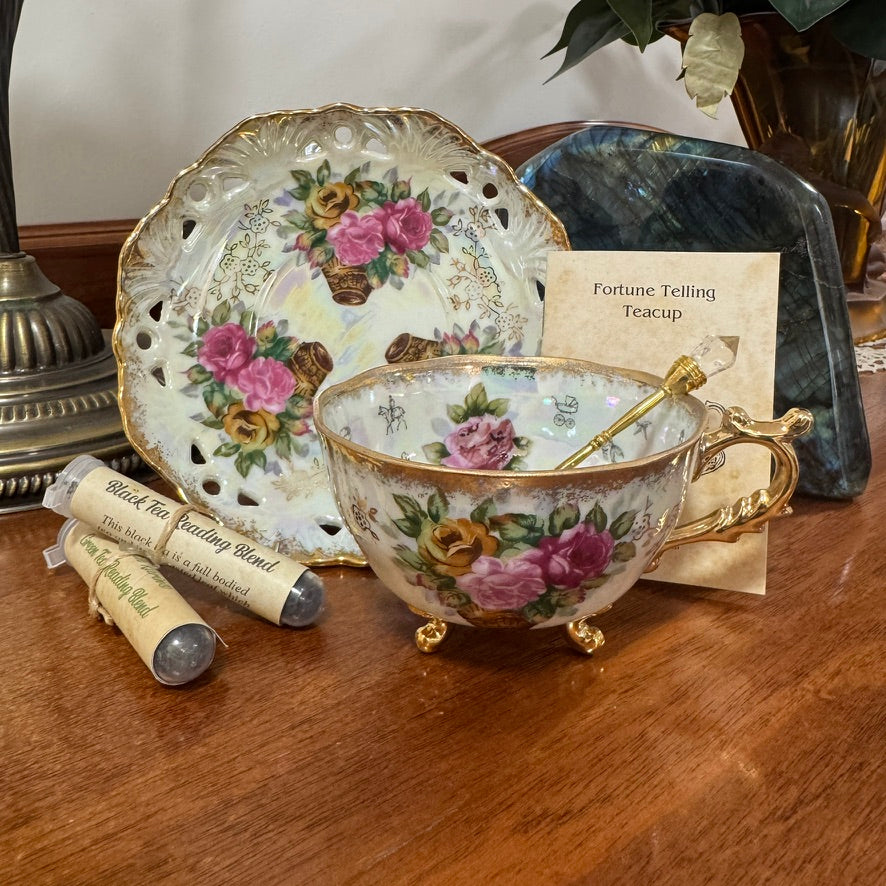 Decorative teacup with floral design on a wooden surface, accompanied by a fortune telling card and tea leaves.