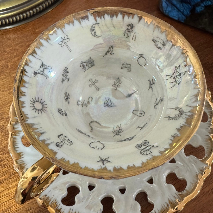 Decorative teacup and saucer with intricate designs on a wooden surface