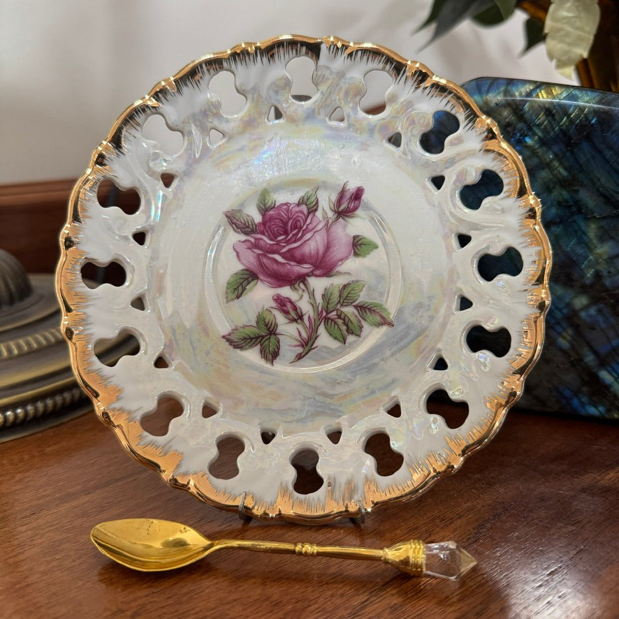 Decorative plate with a rose design and gold rim on a wooden surface